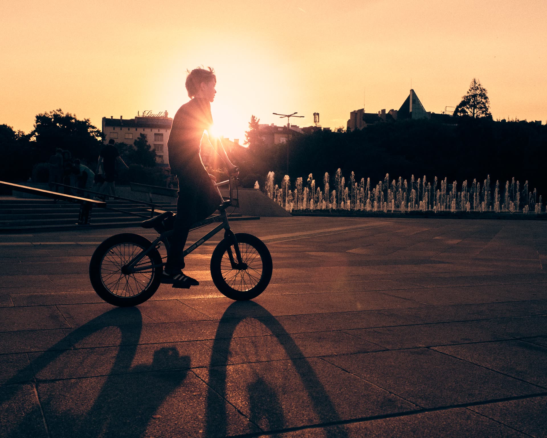 A cyclist crossing a city square at sunset