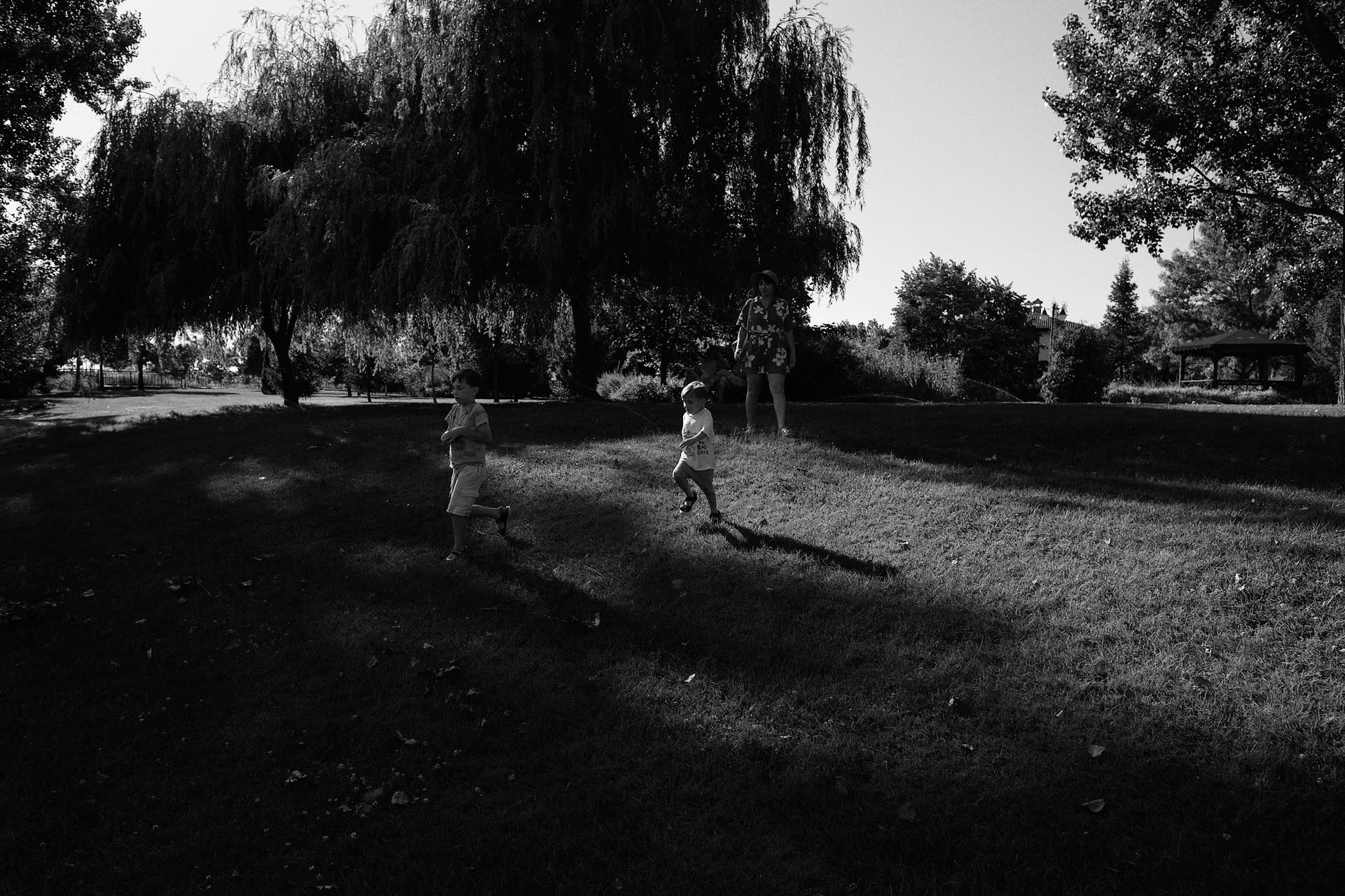 Children running beneath trees in black and white