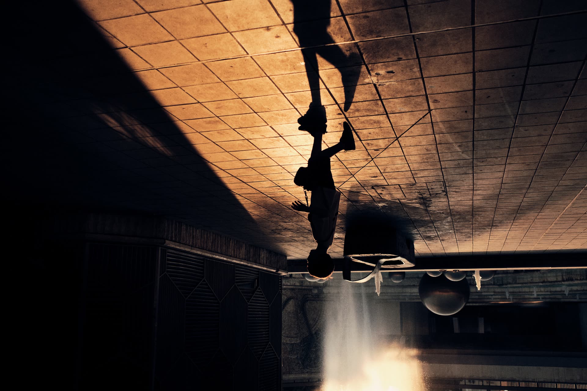 A lone figure mirrored across a reflective ceiling
